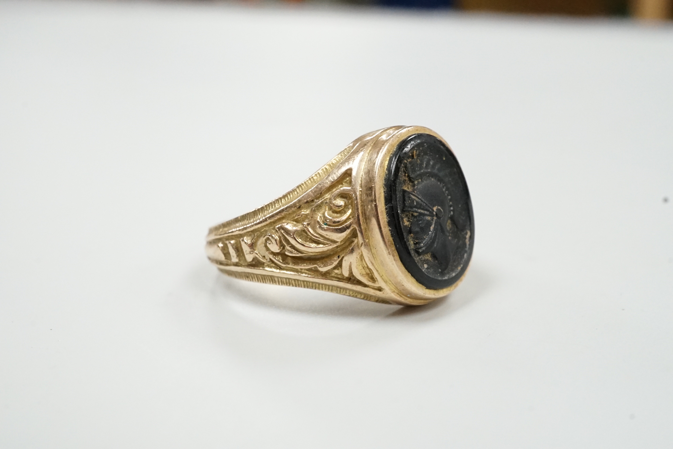 A 1970's 9ct gold and black onyx? set signet ring, carved with the bust of a Roman soldier, size T, gross weight 8 grams.